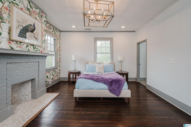 bedroom featuring a fireplace, dark wood-type flooring, and a notable chandelier