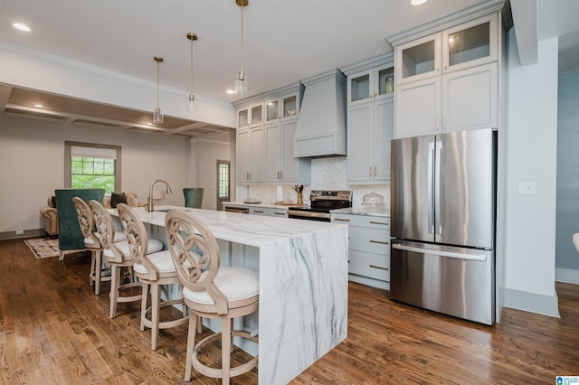 kitchen with premium range hood, a center island with sink, appliances with stainless steel finishes, dark hardwood / wood-style floors, and light stone countertops