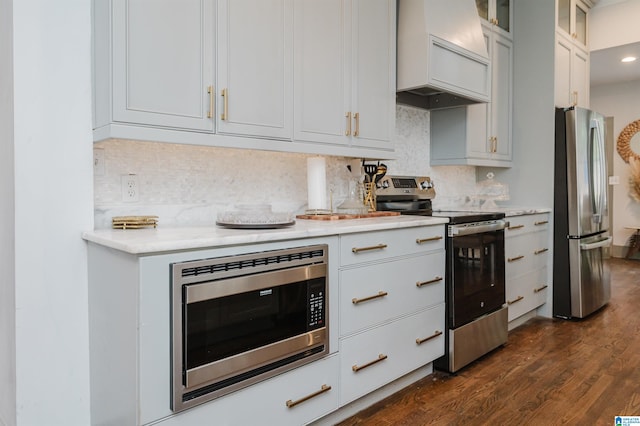 kitchen with stainless steel appliances, white cabinetry, dark hardwood / wood-style floors, backsplash, and premium range hood