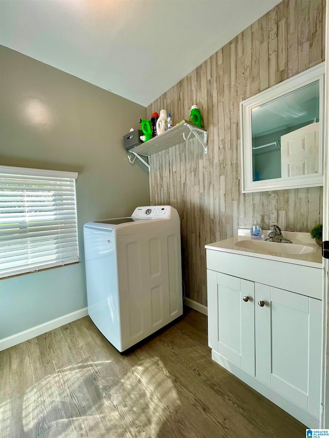 laundry area featuring cabinets, wooden walls, sink, light wood-type flooring, and washer / dryer