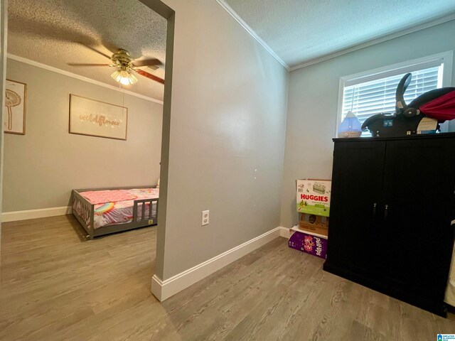 bedroom featuring ornamental molding, a textured ceiling, hardwood / wood-style flooring, and ceiling fan