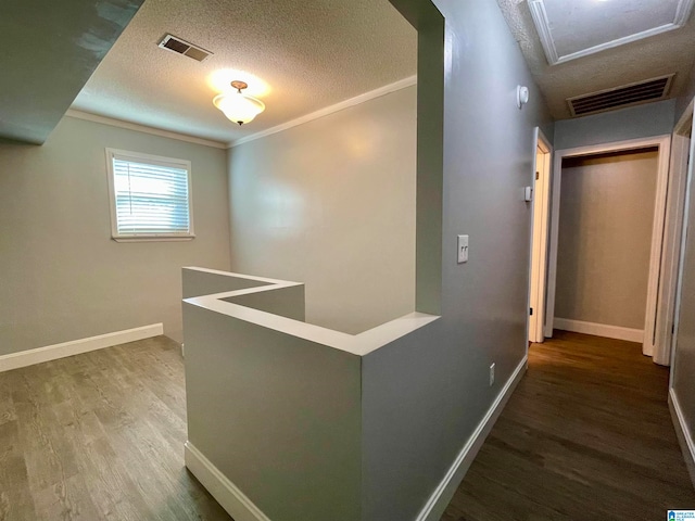 hall featuring hardwood / wood-style floors, crown molding, and a textured ceiling