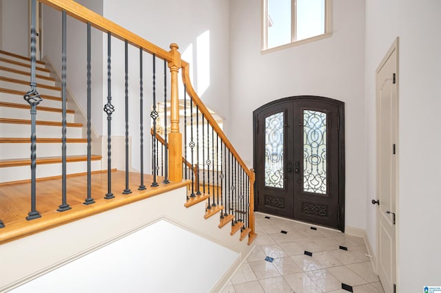 entrance foyer with french doors, light tile patterned floors, and a high ceiling