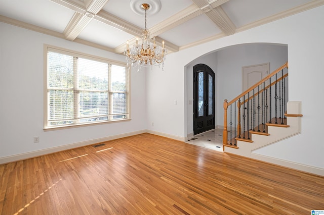 foyer with coffered ceiling, an inviting chandelier, beamed ceiling, crown molding, and hardwood / wood-style floors