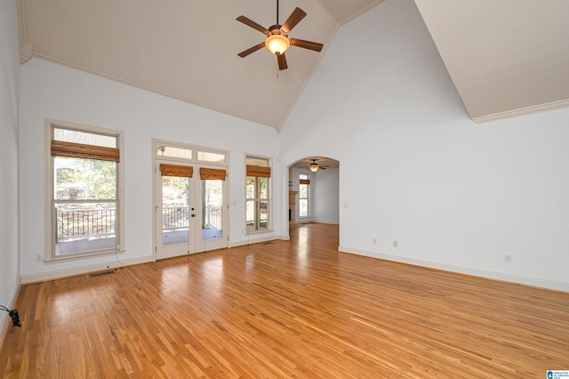 unfurnished living room featuring french doors, light wood-type flooring, high vaulted ceiling, and plenty of natural light