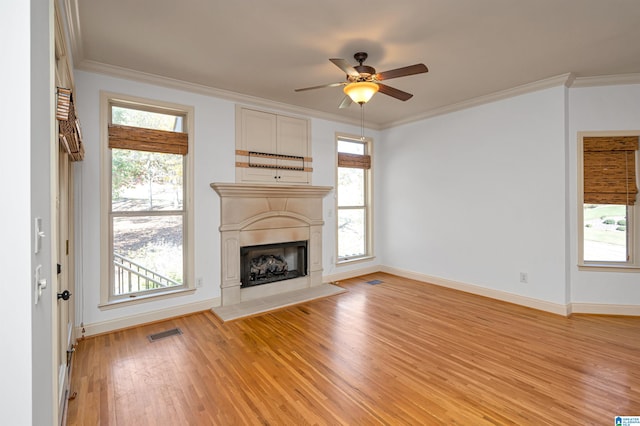 unfurnished living room featuring plenty of natural light, ceiling fan, crown molding, and light hardwood / wood-style flooring