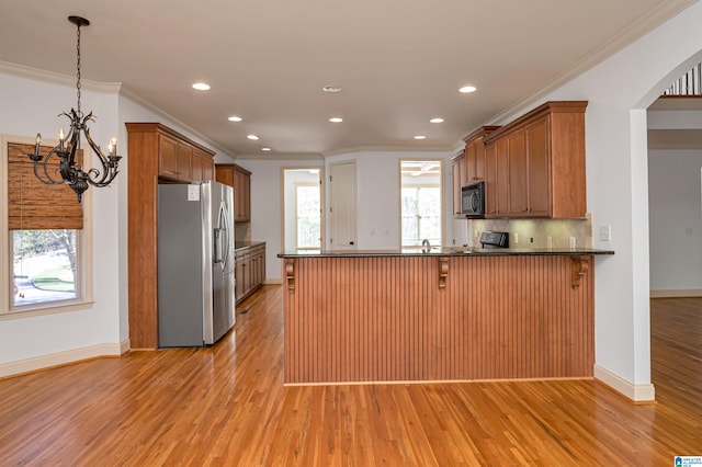 kitchen featuring black appliances, a kitchen breakfast bar, decorative light fixtures, light hardwood / wood-style floors, and kitchen peninsula