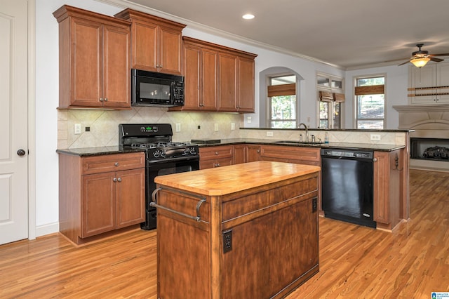 kitchen with black appliances, kitchen peninsula, sink, and light hardwood / wood-style flooring