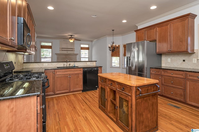 kitchen with sink, a center island, light hardwood / wood-style floors, black appliances, and ceiling fan with notable chandelier