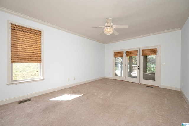 carpeted spare room featuring plenty of natural light, crown molding, and ceiling fan