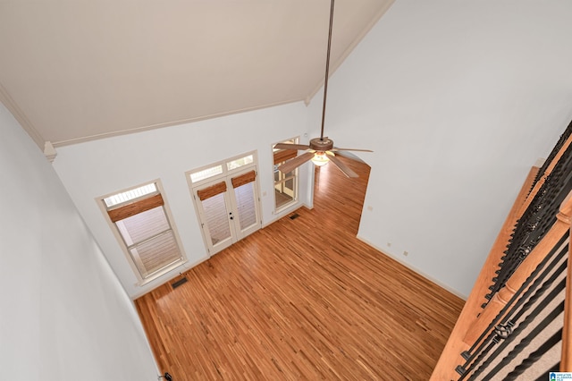 staircase with wood-type flooring, crown molding, and high vaulted ceiling