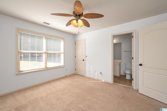 unfurnished bedroom featuring ensuite bath, ceiling fan, and light colored carpet