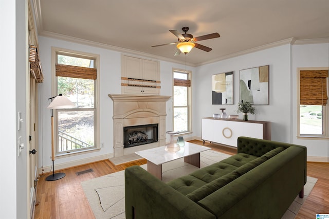 living room featuring ceiling fan, light hardwood / wood-style floors, ornamental molding, and a wealth of natural light