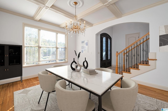 dining area featuring coffered ceiling, crown molding, beam ceiling, light hardwood / wood-style flooring, and a chandelier