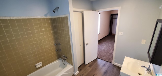 bathroom with hardwood / wood-style floors, vanity, and tiled shower / bath combo