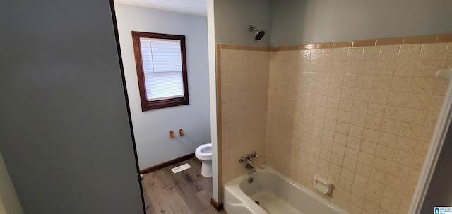 bathroom featuring washtub / shower combination, hardwood / wood-style flooring, and toilet