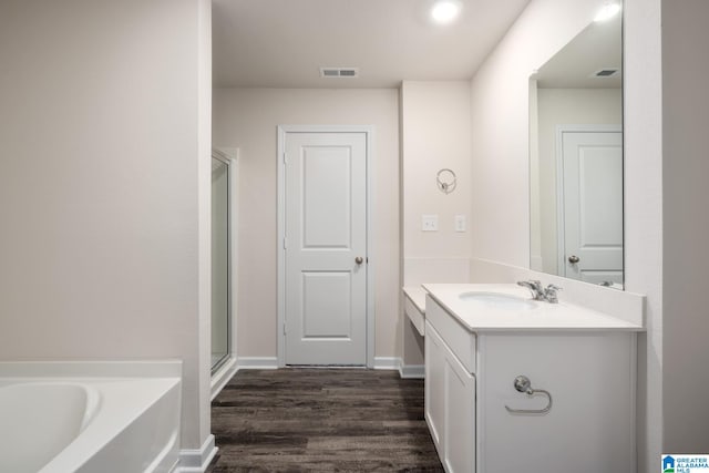 bathroom featuring hardwood / wood-style flooring, vanity, and plus walk in shower