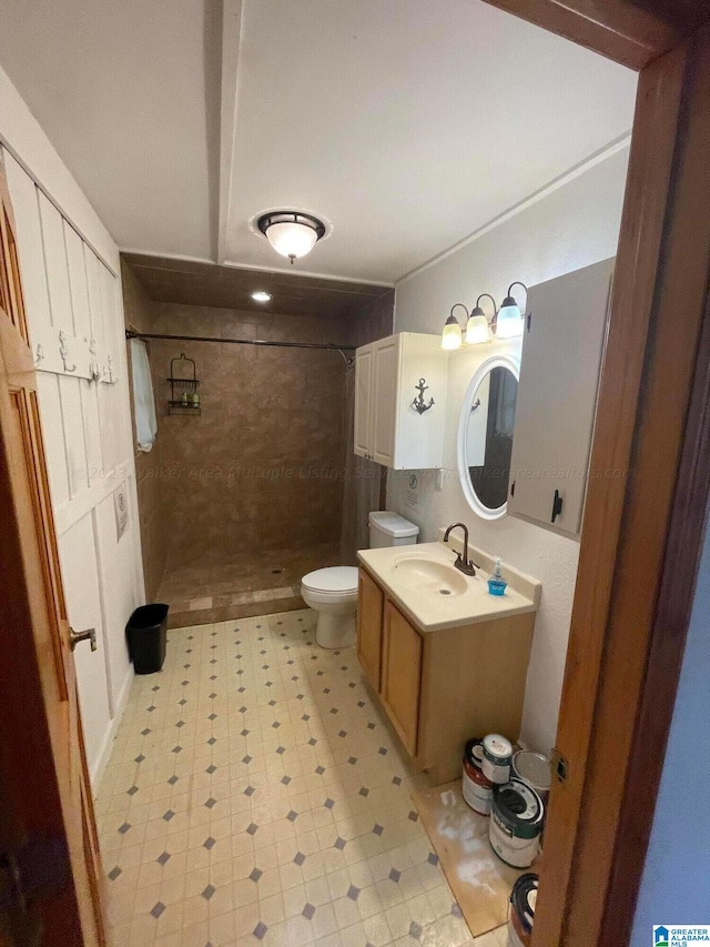 bathroom with toilet, vanity, and tiled shower