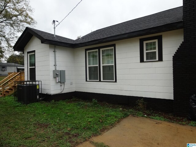 1317 SW 16th St SW, Birmingham, AL 35211 - view of side of home featuring central AC, a patio area, a shingled roof, and a lawn