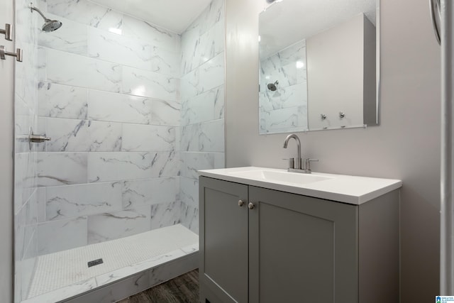 bathroom featuring vanity, wood-type flooring, and tiled shower