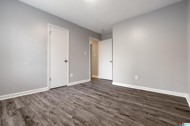 spare room with a textured ceiling and dark hardwood / wood-style floors