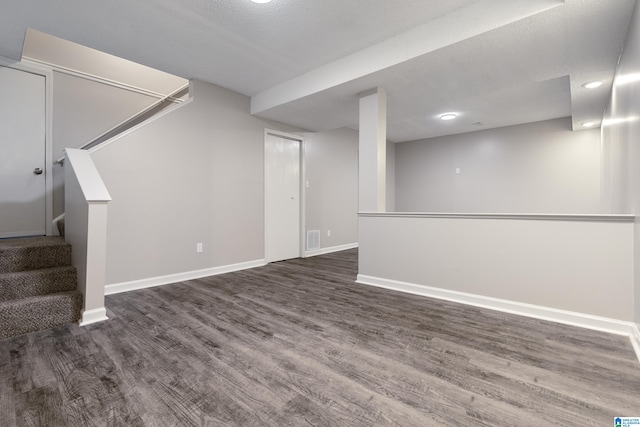 basement with a textured ceiling and dark hardwood / wood-style floors