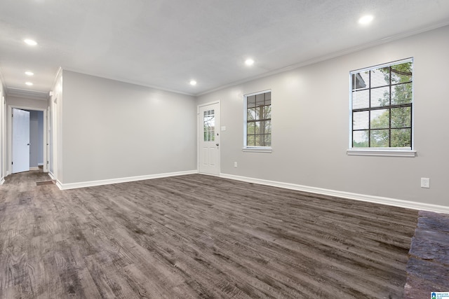 empty room featuring a wealth of natural light, dark hardwood / wood-style floors, and ornamental molding