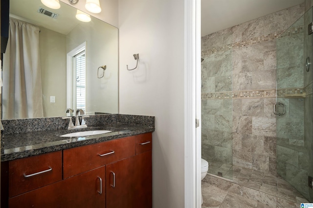 bathroom with walk in shower, vanity, and toilet