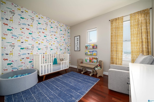 bedroom featuring a crib and dark wood-type flooring