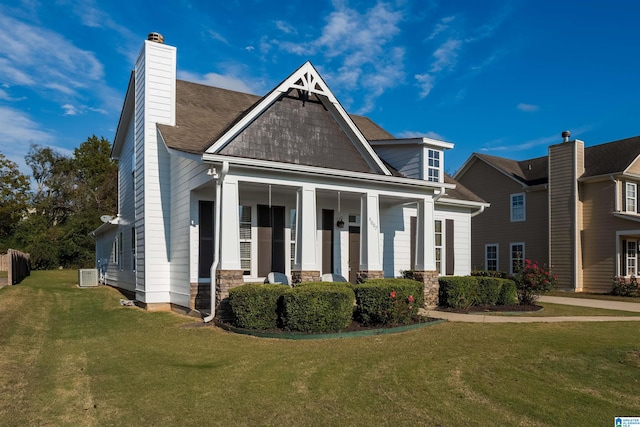 craftsman-style house featuring central AC, a front yard, and covered porch