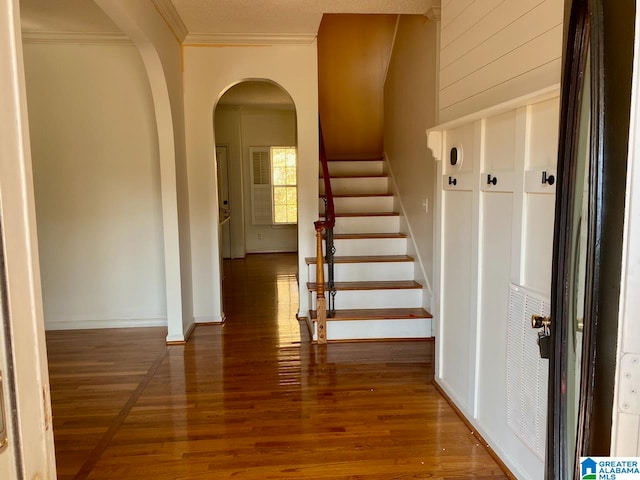 stairs with hardwood / wood-style flooring and crown molding