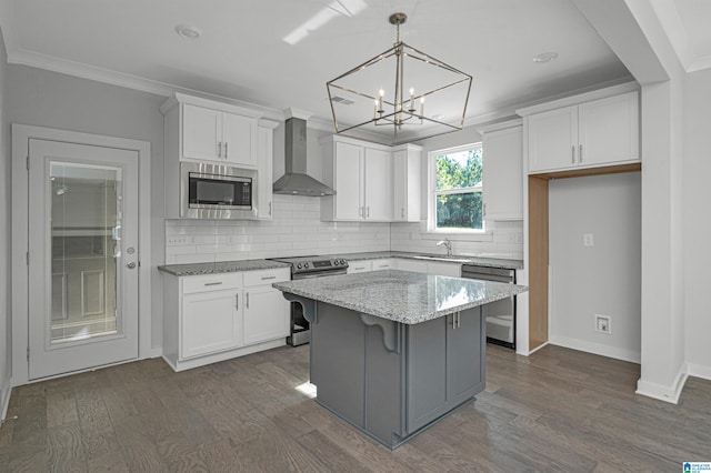 kitchen featuring white cabinetry, appliances with stainless steel finishes, wall chimney exhaust hood, a center island, and dark wood-type flooring