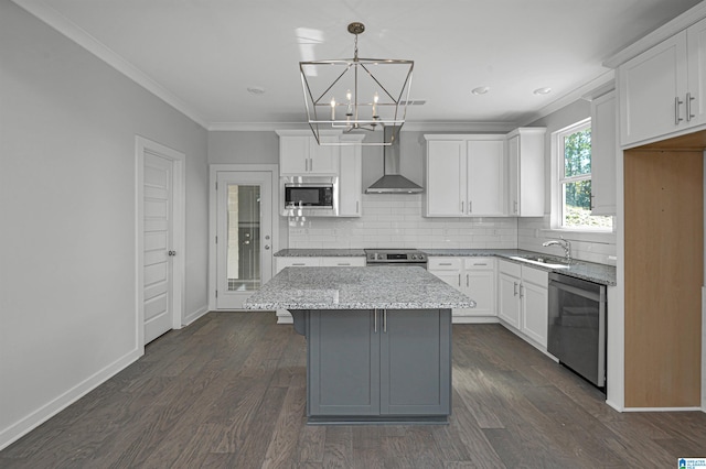 kitchen featuring white cabinets, wall chimney exhaust hood, appliances with stainless steel finishes, and a center island