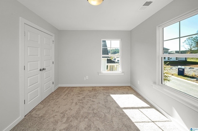 unfurnished bedroom with light colored carpet and a closet