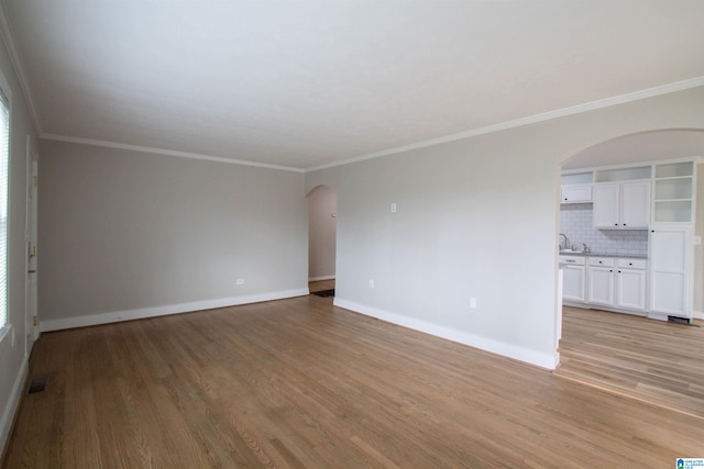 spare room with light wood-type flooring, a healthy amount of sunlight, and crown molding