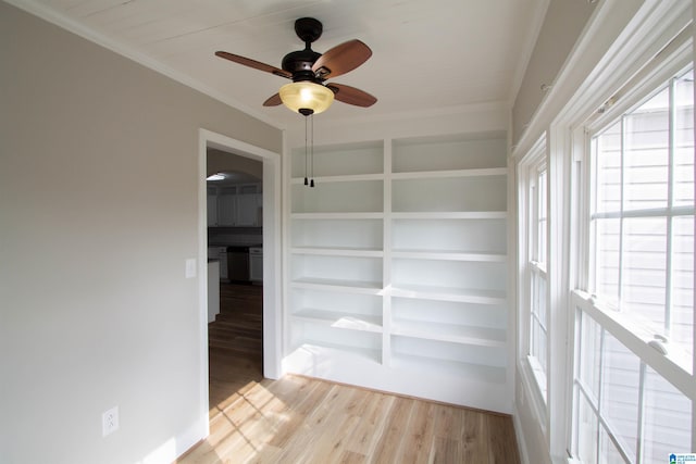 unfurnished room featuring ornamental molding, light wood-type flooring, built in shelves, and ceiling fan