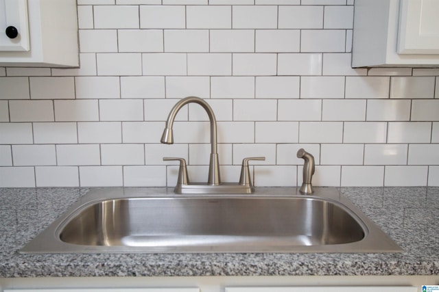 interior details with dark stone counters, tasteful backsplash, sink, and white cabinets