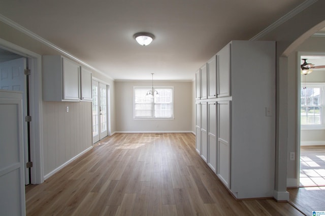 interior space featuring a wealth of natural light, ceiling fan with notable chandelier, light hardwood / wood-style floors, and ornamental molding