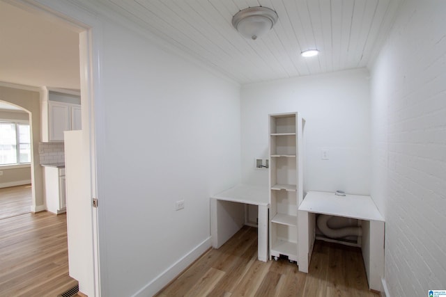 office with light wood-type flooring, wooden ceiling, crown molding, and brick wall