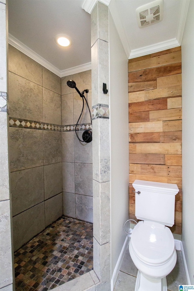 bathroom with tiled shower, toilet, wood walls, and crown molding