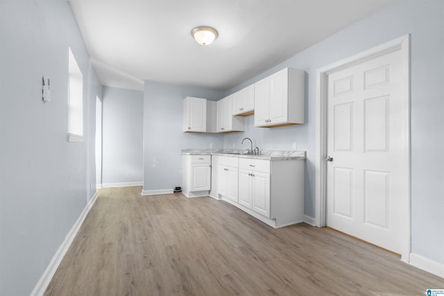 kitchen with white cabinets, light wood-type flooring, and sink