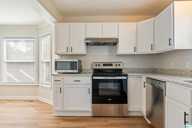 kitchen with white cabinets, light hardwood / wood-style floors, light stone countertops, and appliances with stainless steel finishes