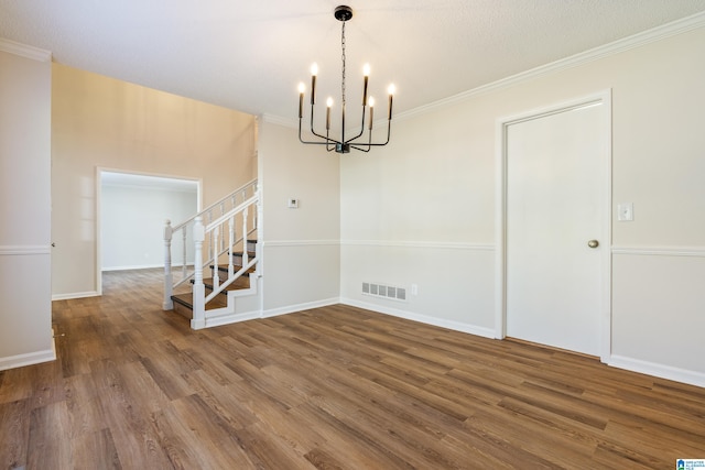 unfurnished dining area with hardwood / wood-style floors, a textured ceiling, a notable chandelier, and ornamental molding