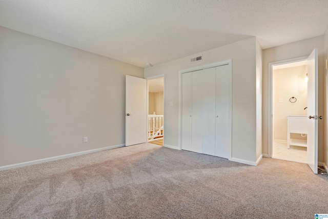 unfurnished bedroom with a textured ceiling, light carpet, and a closet