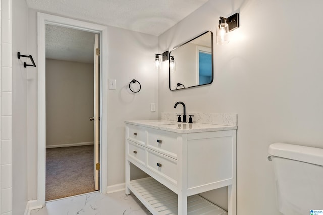 bathroom with toilet, vanity, and a textured ceiling