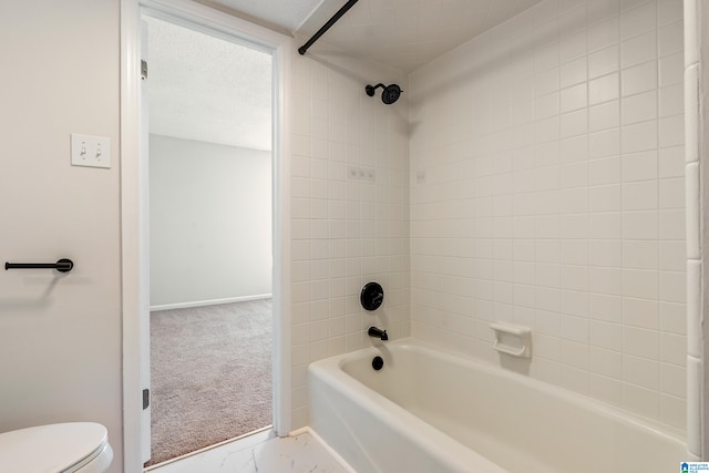 bathroom with tiled shower / bath, a textured ceiling, and toilet