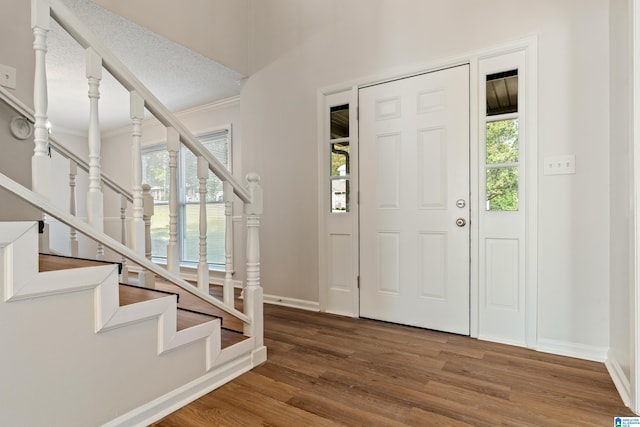 entryway with a textured ceiling, hardwood / wood-style flooring, and crown molding