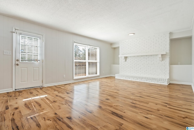 unfurnished living room featuring a textured ceiling, light hardwood / wood-style floors, and plenty of natural light