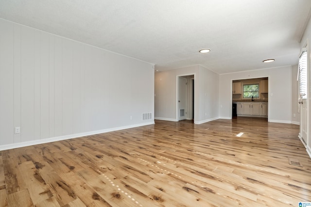 unfurnished living room featuring a textured ceiling and light hardwood / wood-style floors