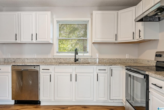 kitchen with stainless steel appliances, white cabinets, sink, light stone countertops, and extractor fan